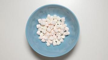 vista de cima: marshmallows enchem um prato azul (stop motion)