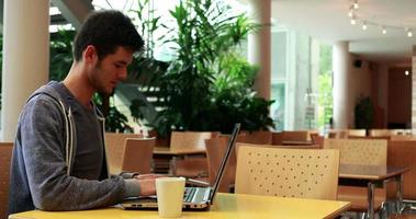 lachende student zitten en met behulp van zijn laptop video