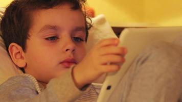 cara de un niño lindo con una tableta blanca en casa video