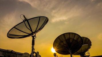 Silhouette of satellite dish and clouds in time-lapse video