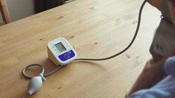 vista traseira: um homem idoso medindo a pressão arterial em casa