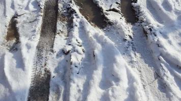 bandes de roulement et empreintes de pas dans la neige, rue de la ville couverte de neige. video