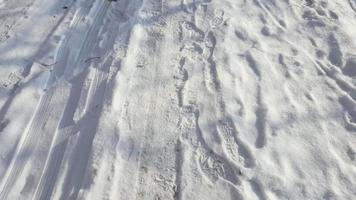 slitbanor och fotspår i snö, stadsgata täckt av snö.