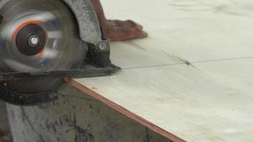 bouwvakker houten planken snijden met elektrische cirkelzaag buitenshuis