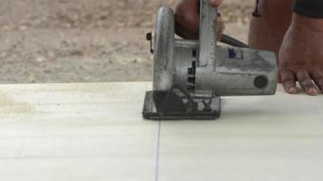 Construction worker cutting wood planks with circular electric saw outdoors