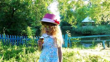bambina con i capelli lunghi mangia il gelato nel parco. video