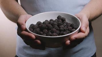A dish with a blackberries in a male hands