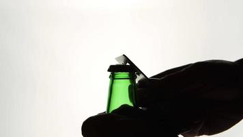 la silhouette delle mani maschile che aprono la bottiglia di birra marrone con l'apri video