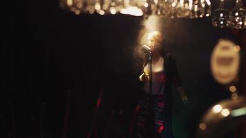 skrubbkvinna dansar och sjunger på scenen i vintage mikrofon i rampljuset. rök video