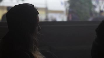 Silhouette of girl in cap sit in room. Steam around her. Looking in window video