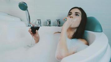 Mädchen entspannen in Bad voller Schaum. rauchen elektronische Zigarette, Dampf, Rotwein