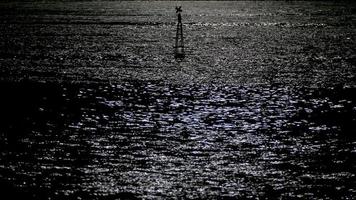 Reflection of moonlight sea with a lighted buoy.