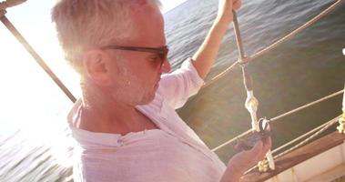 lächelnder Mann auf seiner Yacht, der seinen Kompass auf Richtung prüft video