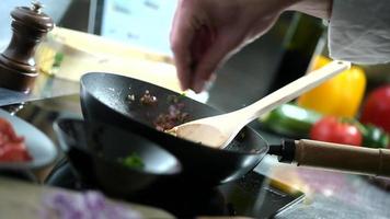 junger Mann in seiner Küche steckte gehackte Kräuter in ihre Pfanne video