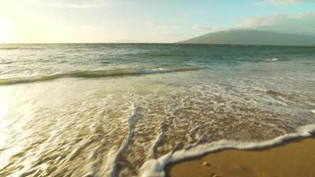 geweldige zonsondergang over tropisch strand. golven rollen in slow motion wit zand op. luxe resort vakantie video