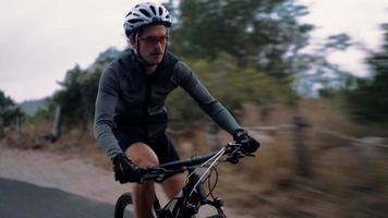 Ciclista decidido en persecución recreativa con bicicleta en carretera de montaña video