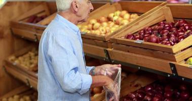 Senior man picking out apples in supermarket