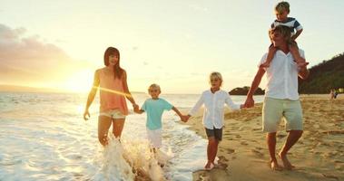 gelukkige familie op het strand bij zonsondergang