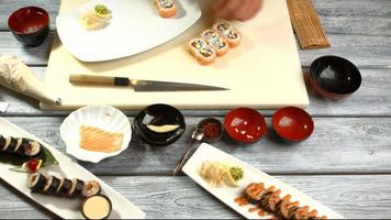 manos ponen sushi en un plato. video