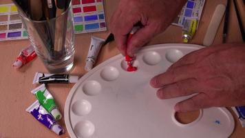 Red and yellow gouache tubes are poured into the palette video