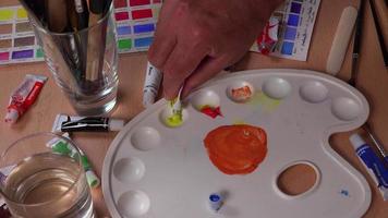 Yellow and blue gouache tubes are poured into the palette video