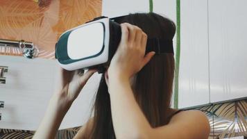 Girl sitting in bathroom in virtual reality glasses on head. Looking around video