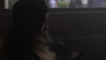 Silhouette of girl in cap hold electronic cigarette in hands Vaper. Steam video