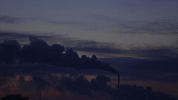 Winter Sonnenaufgang über der Stadt. Rauch aus dem Schornstein. Starker Wind treibt Wolken an. Zeitrafferaufnahmen.