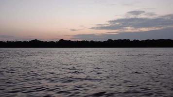 de kano van de kleine visser op rivier onder bewolkte zonsopgang