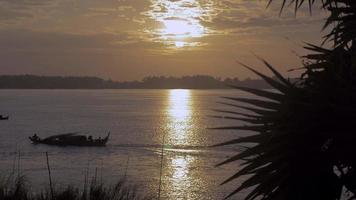 pequeno barco motorizado ao nascer do sol refletindo no rio video