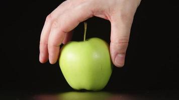 mänsklig hand tar bort hälften av grönt äpple