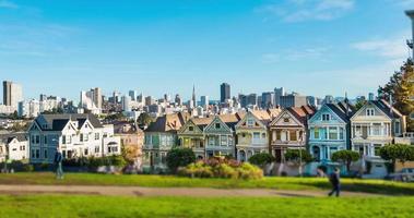 lapso de tempo com casas vitorianas na steiner street com o horizonte de São Francisco atrás.