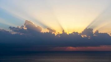 timelapse av solstrålar dyker upp även om molnen vid soluppgången över havet. video