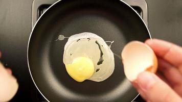 bovenaanzicht: menselijke handen legt ei op de koekenpan