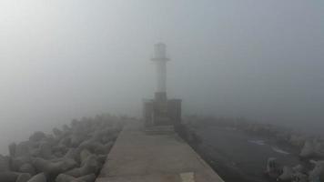 mystieke ochtend, vuurtoren in dichte mist en mist, luchtfoto video