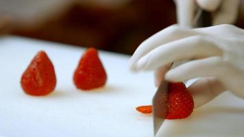 Hand with knife cuts strawberry.
