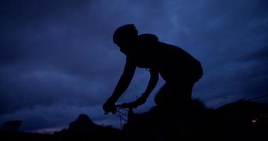 Plan vers le haut de la silhouette du cycliste à la poursuite avec vélo sur route de montagne
