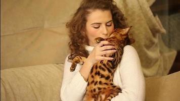 la niña abraza y besa a un gato de bengala.