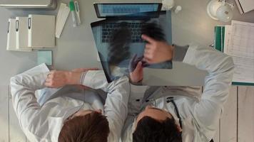 Vista superior de los médicos discutiendo la radiografía de los intestinos en el consultorio médico video