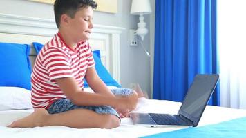 bambino sdraiato su un letto e utilizzando il computer portatile video