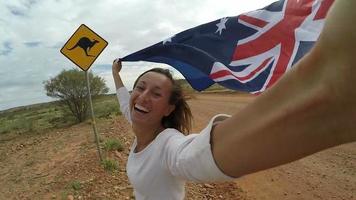jonge vrouw neemt selfie portret op weg naast kangoeroe waarschuwingsbord