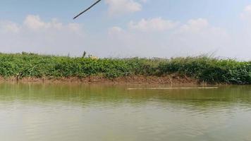 förbi en husbåt med ett kinesiskt fisknät längs floden