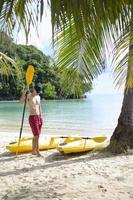 hombre en la playa con kayak remo foto