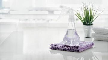 Botella de spray y una toalla sobre la mesa blanca en la cocina foto