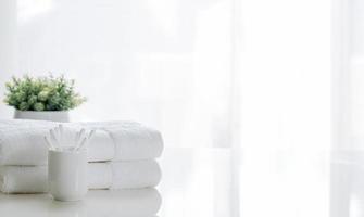 White towels on a table with a plant photo