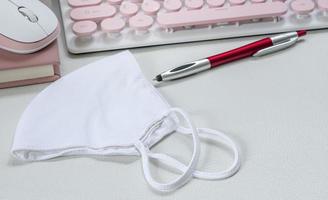 Face mask on a desk with a keyboard and pen photo