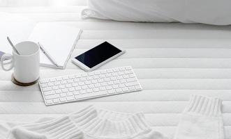 café con un teclado y un teléfono inteligente en una cama foto