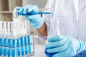 Scientist pouring liquid into a flask photo