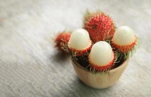 Pelar rambután en tazón de madera foto