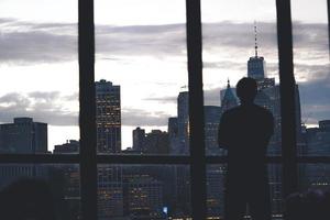 hombre de pie cerca de la ventana de la ciudad foto